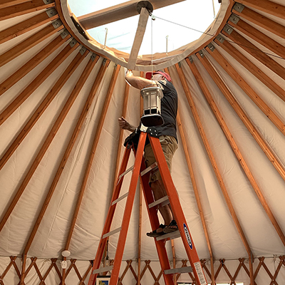 Earl Lewis installs a hanging dome light in his yurt.