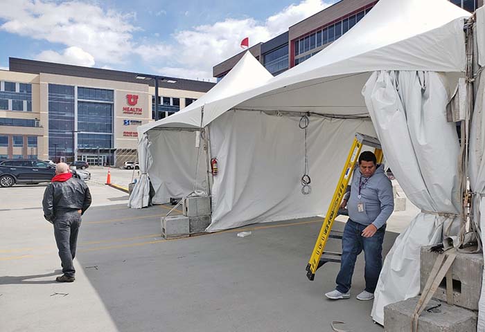 Josue Smith, carrying the ladder, installs cable in a COVID tent at the University of Utah Health's Sugar House Health Center (photo courtesy of Liz Navarro).