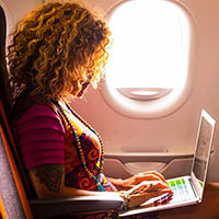 Person on an airplane typing on a laptop computer.