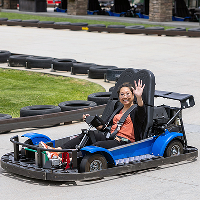 Kim Tanner, director for UIT Platform Services, waves while taking a spin around the go-kart track at Boondocks Food & Fun in Draper