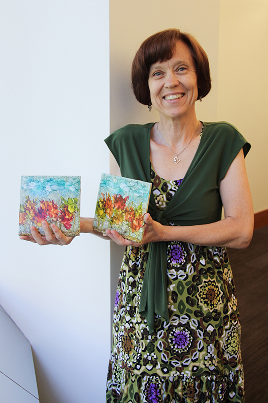 Cindy Hanson holding two pieces of artwork