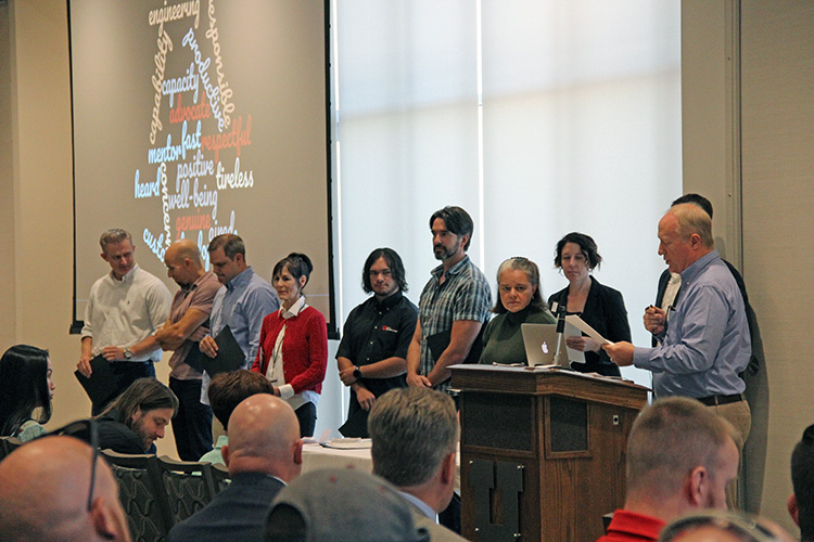 L-R: Kevin Taylor Memorial Service Award nominees Jason Moeller, Matt Leatham Rob Lake, Robin Horton, Danial Ebling, and Rob Birkinshaw stand beside committee members Shellie Eide, Rachael Sheedy, Jesse Drake, and Bryan Morris during the presentation at the September 17 All-Hands Meeting at the Alumni House. Not pictured: Craig Bennion, Vijay Kammili, Chris Moore, Anita Orendt, and Judy Yeates.