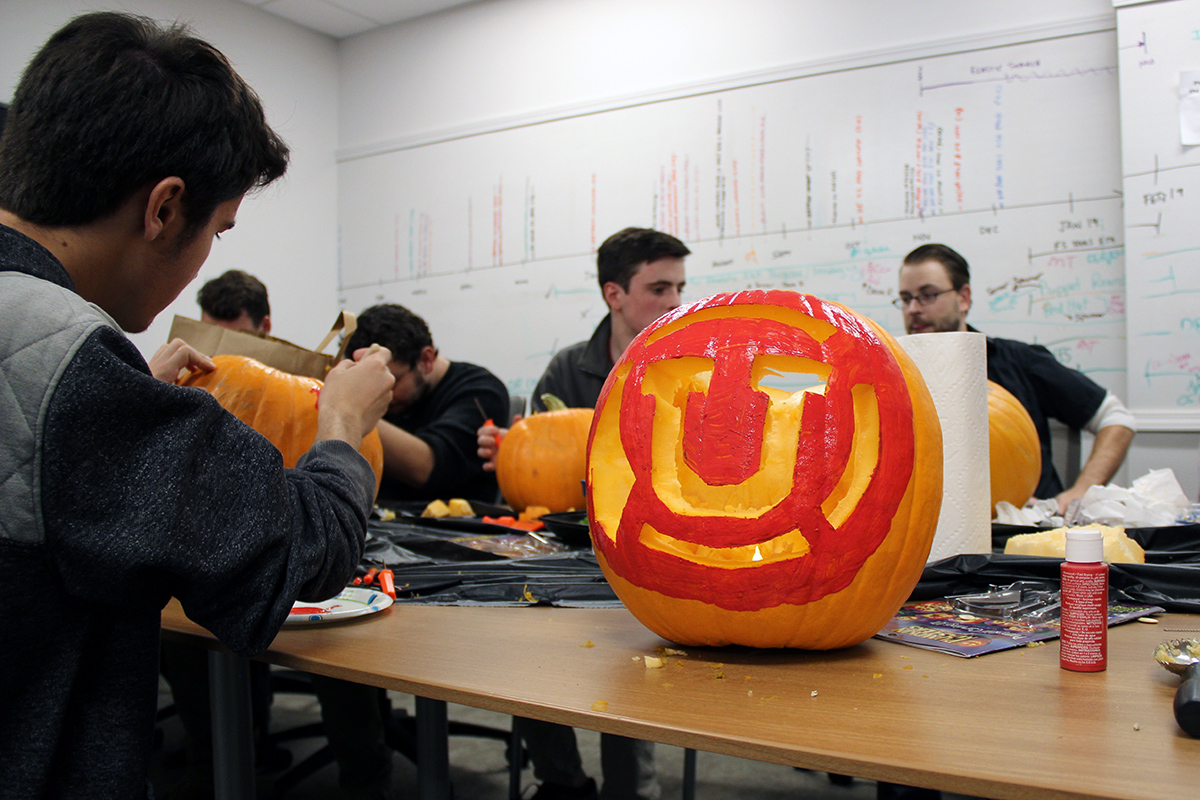 Bryce Saldajeno, student intern in USS Quality Assurance, digs in during a pumpkin carving contest on October 12. The jack-o'-lantern at right was created by Jason Moeller, associate director of USS Engineering.