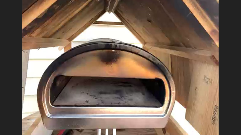Brian Harris' pizza oven sits inside a small wooden house-like structure.