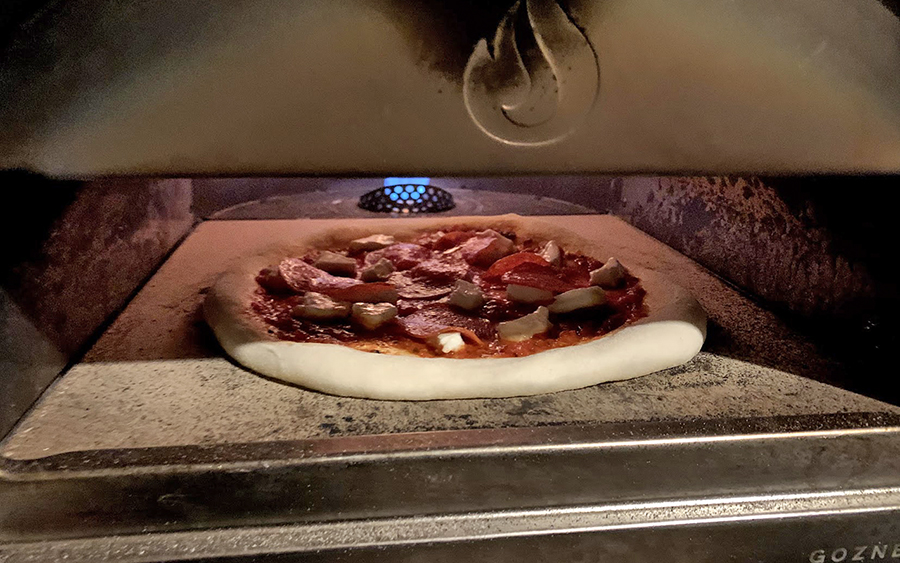 The oven bakes pizza with propane or wood.