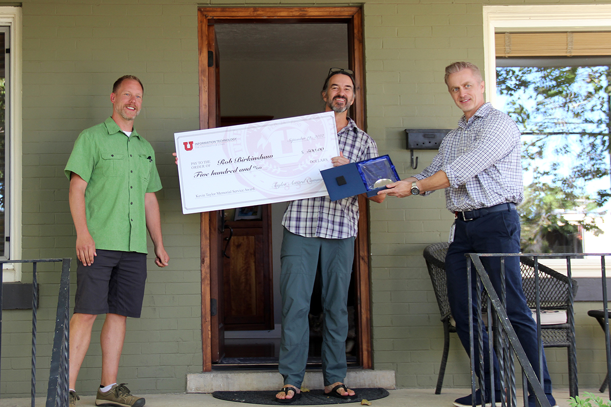 Rob Birkinshaw, center, is congratulated by Dustin Udy, left, and Jason Moeller, right, for winning the 2022-23 Kevin Taylor Memorial Service Award. Award committee members greeted Birkinshaw at his home with a plaque and large check that represents a $500 honorarium.