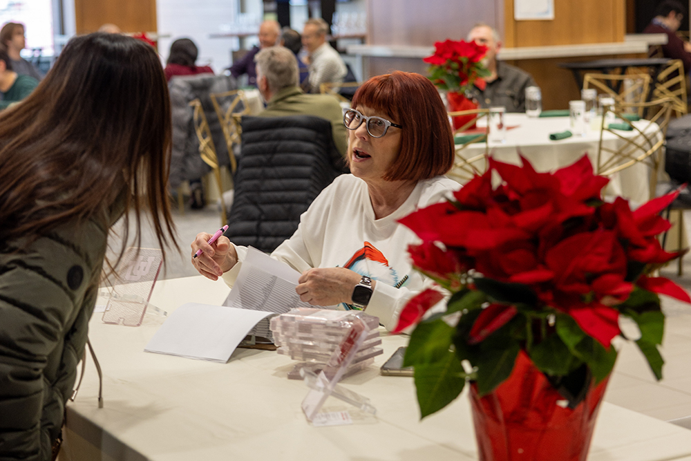 Jan Lovett signs in a guest at the 2024 UIT Holiday Party