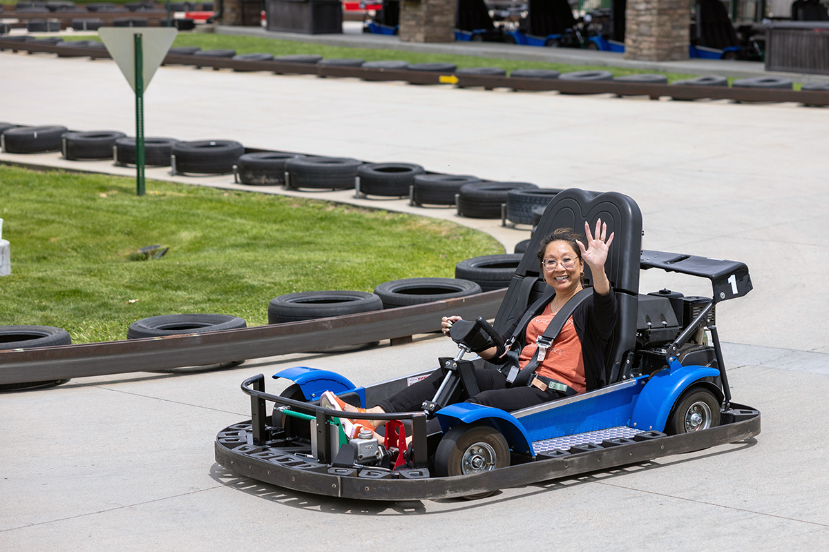 Kim Tanner, director of UIT Platform Services, waves while taking a spin around the go-kart track at Boondocks Food & Fun in Draper. (Photo courtesy of Thanh Nguyen)